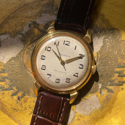 Reloj Kirovskie vintage de la década de 1970 en oro chapado con dial de champán y pulsera de cuero negro